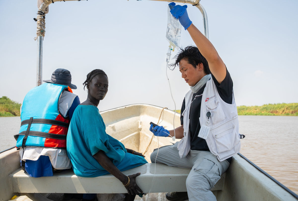 Ein Mitarbeiter von Ärzte ohne Grenzen versorgt eine Patientin auf einem Boot